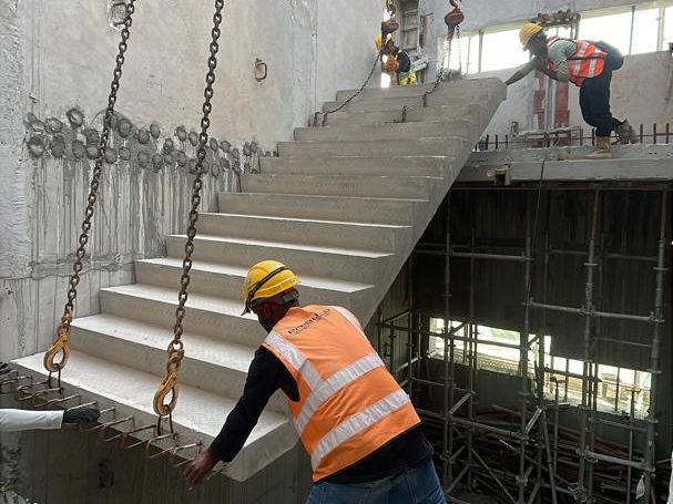 A precast staircase flight being lifted into the stair core on chains