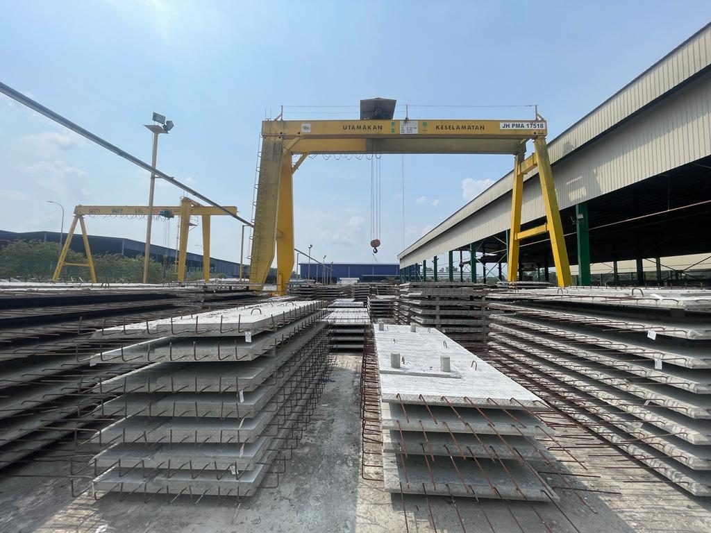 Stacks of precast half slabs in the yard beneath the gantry crane