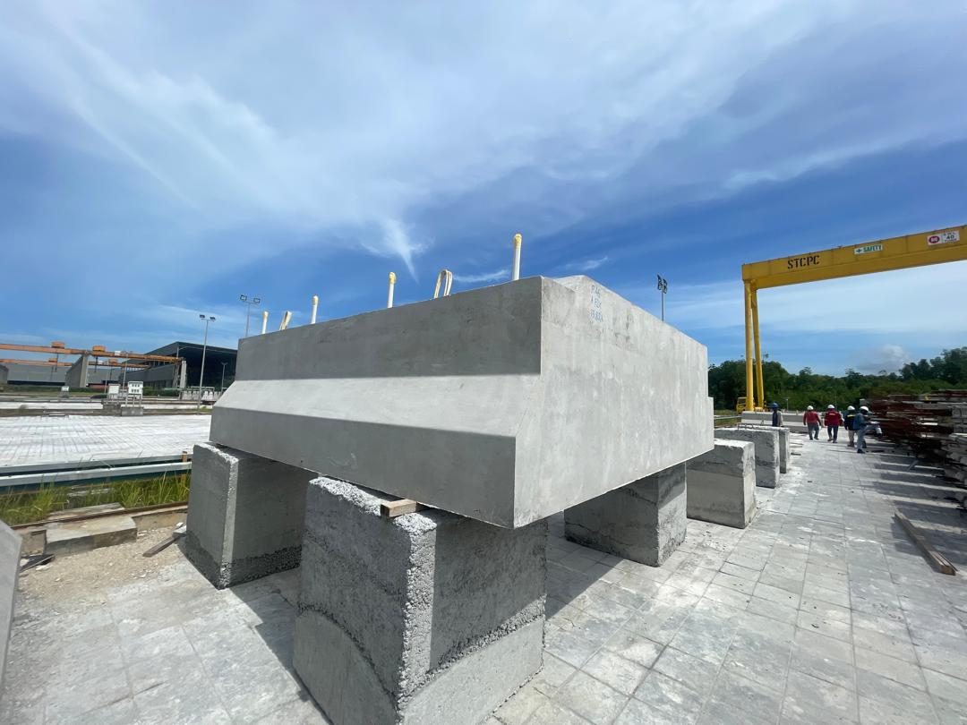 A large off-form concrete unit with chamfered faces standing in the casting yard