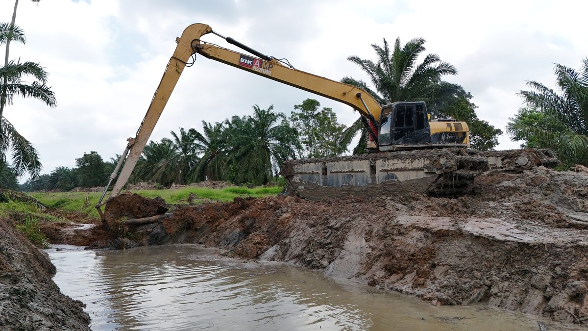 Long-reach excavator on the bank reaching into the water of a channel