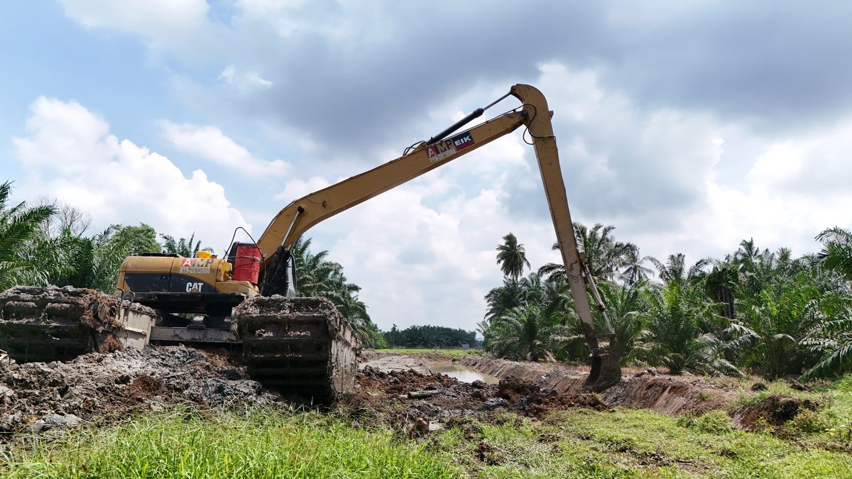 Long-reach excavator on a new embankment under a cloudy sky